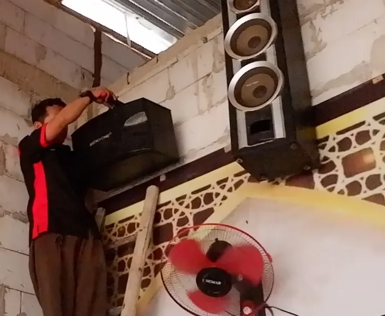 Teknisi sedang melakukan instalasi speaker Audio One di dinding masjid Jakarta untuk sistem suara azan dan pengajian yang jernih.