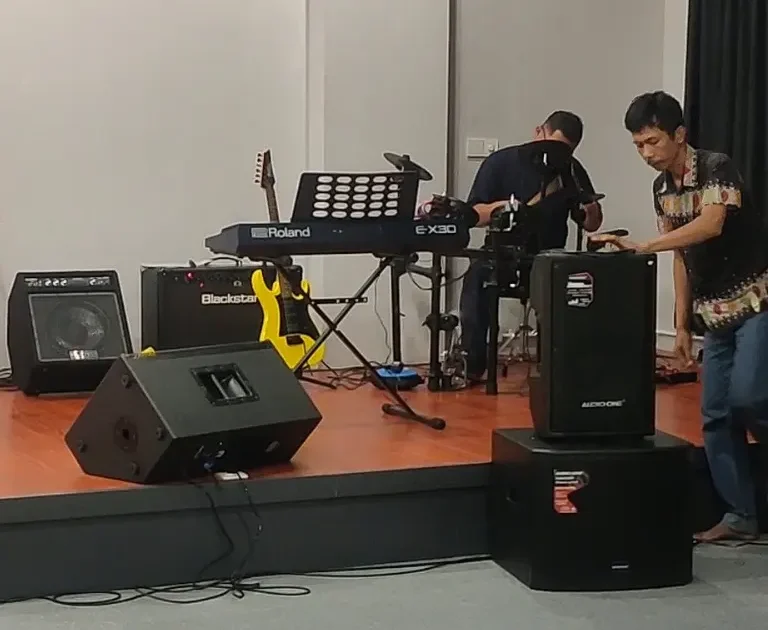 Pengaturan sistem monitor panggung menggunakan speaker Audio One di sebuah studio sekolah musik Jakarta dengan instrumen keyboard dan gitar.