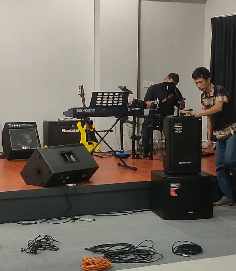 Pengaturan sistem monitor panggung menggunakan speaker Audio One di sebuah studio sekolah musik Jakarta dengan instrumen keyboard dan gitar.